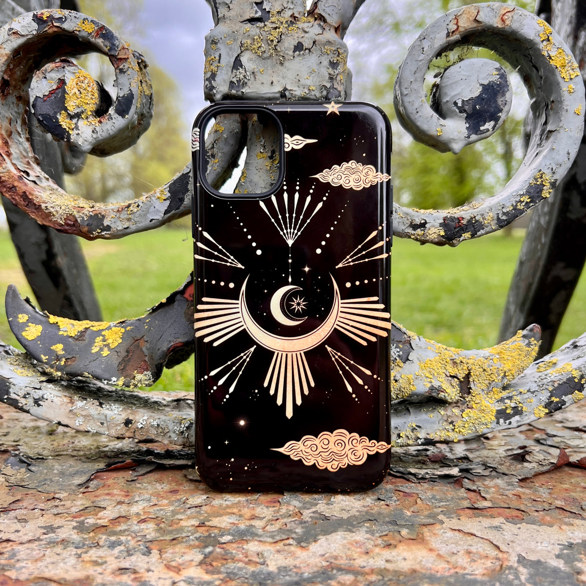 Black iPhone tough case featuring a gold celestial crescent moon, stars, and cloud design on a glossy, dual-layer shell.