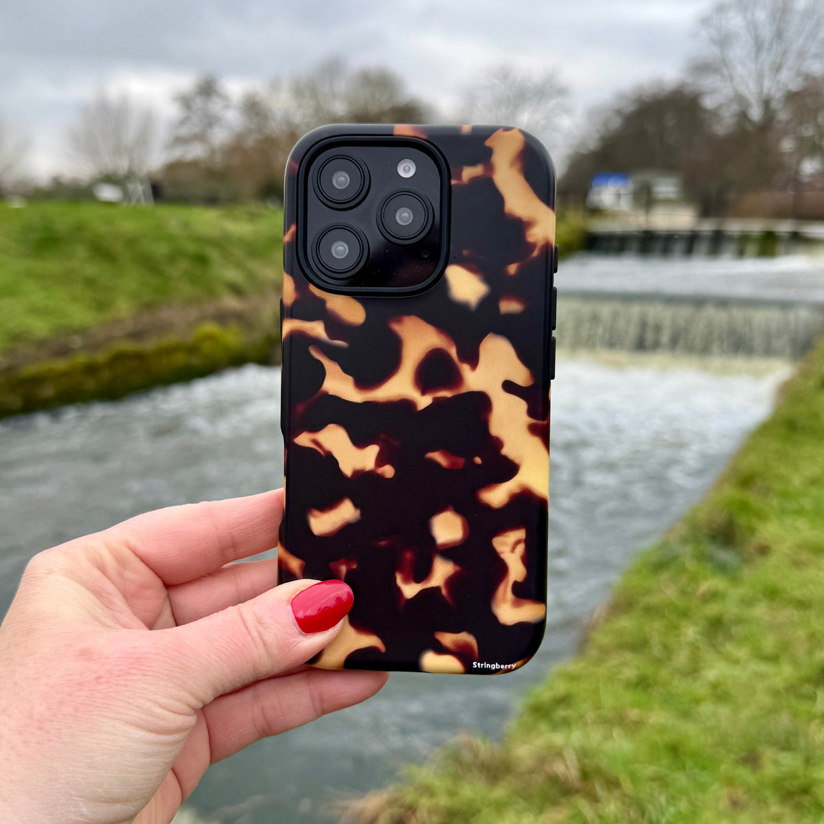 iPhone Tough Case in Lava featuring a black and amber tortoiseshell pattern with dual-layer protection and camera cutouts.