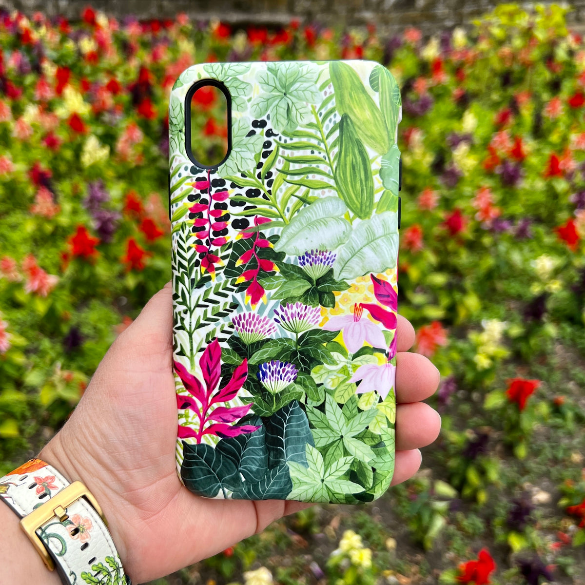 Durable iPhone tough case featuring a vibrant Pink Botanical floral print by Bex Parkin held against a garden background.