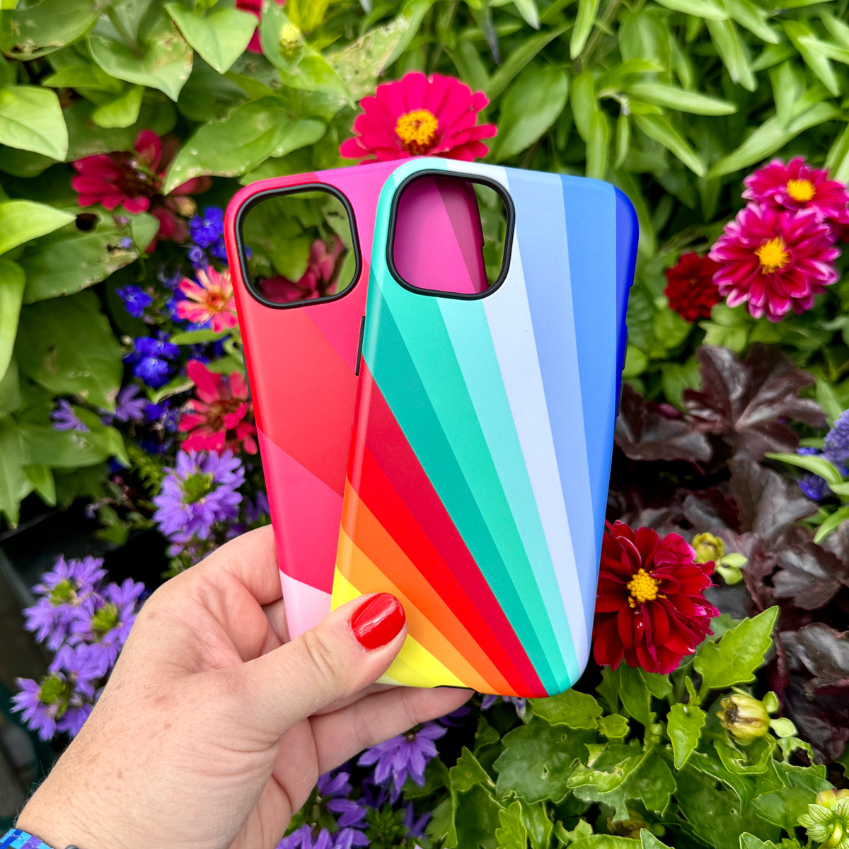Two iPhone tough cases featuring a vibrant, multi-colored Spectrum Fan design held against a backdrop of colorful flowers.