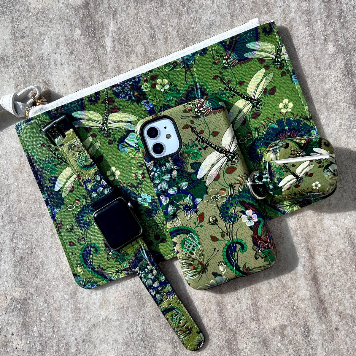 Vyne iPhone Tough Case featuring a green dragonfly and floral print, shown with matching accessories on a stone surface.