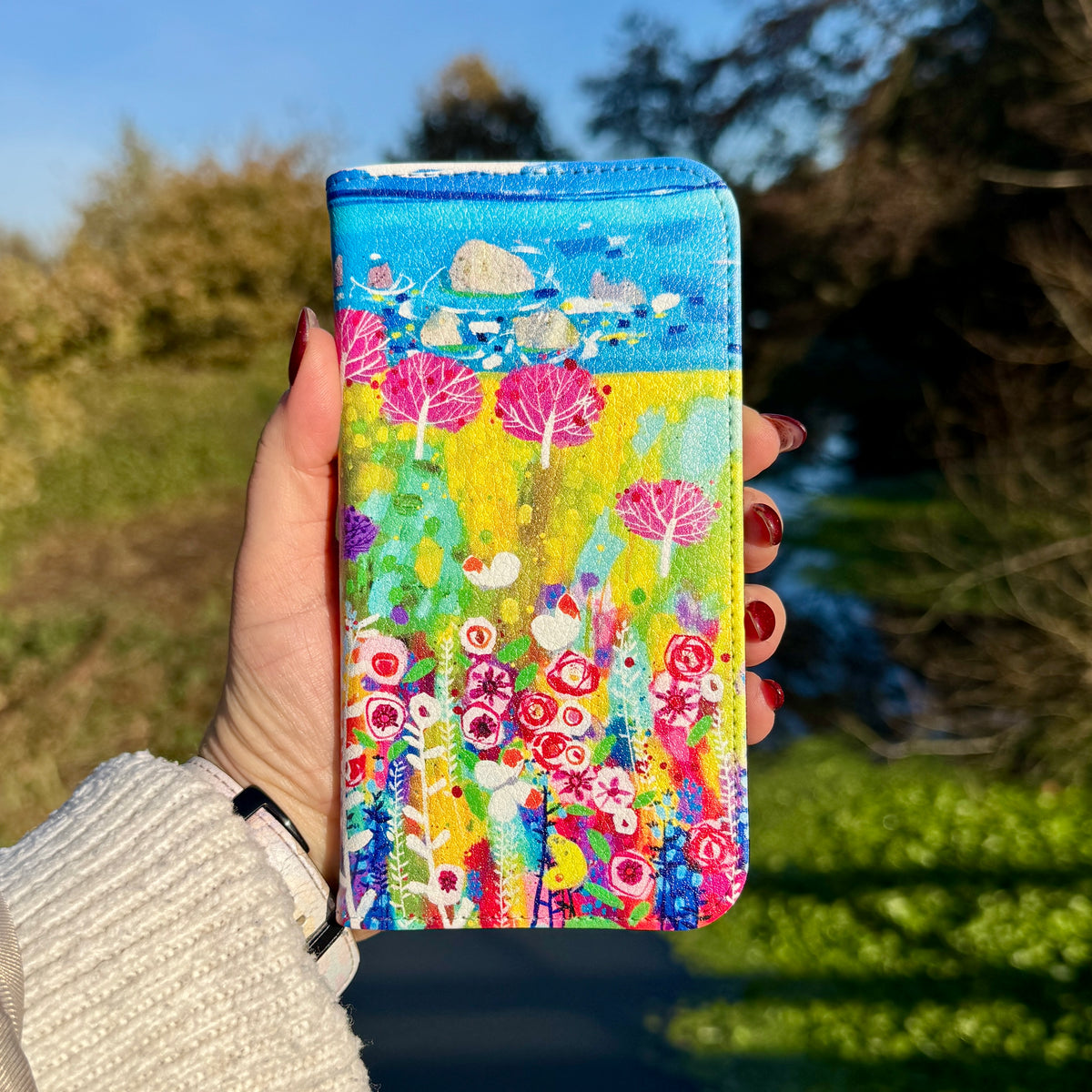 Vegan leather folio phone case featuring Claire West's colorful Precious Day floral artwork with a smooth satin finish.