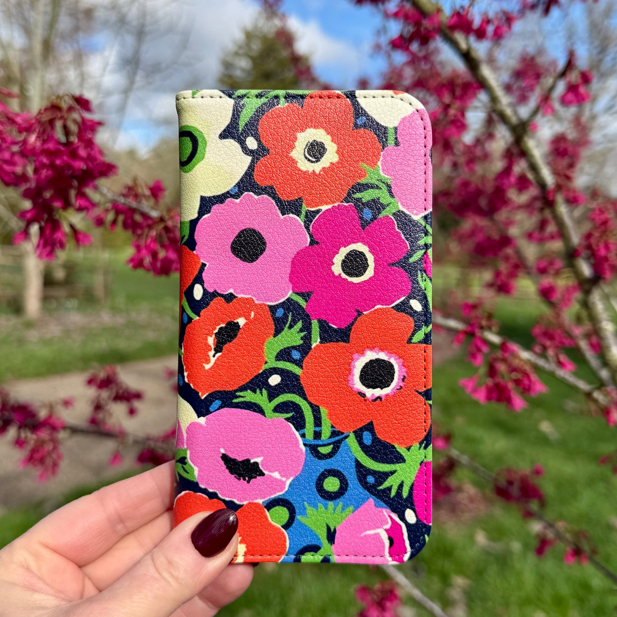 Vegan leather folio phone case featuring a vibrant Windflowers floral print in red, pink, and blue with a satin finish.