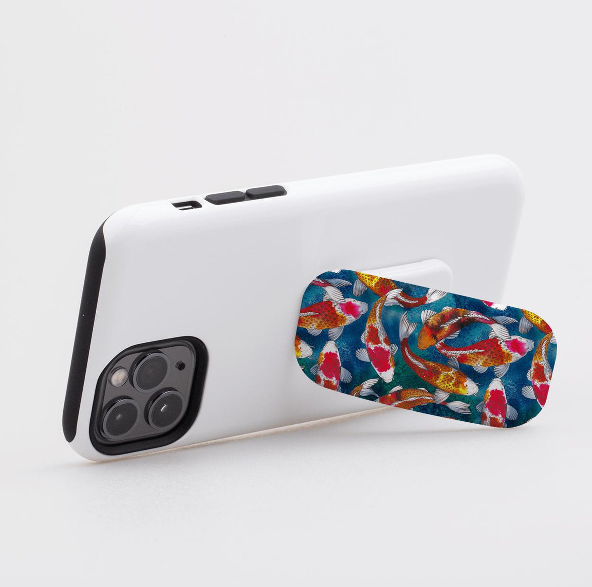 Adachi phone stand with a vibrant koi fish pattern attached to the back of a white smartphone.