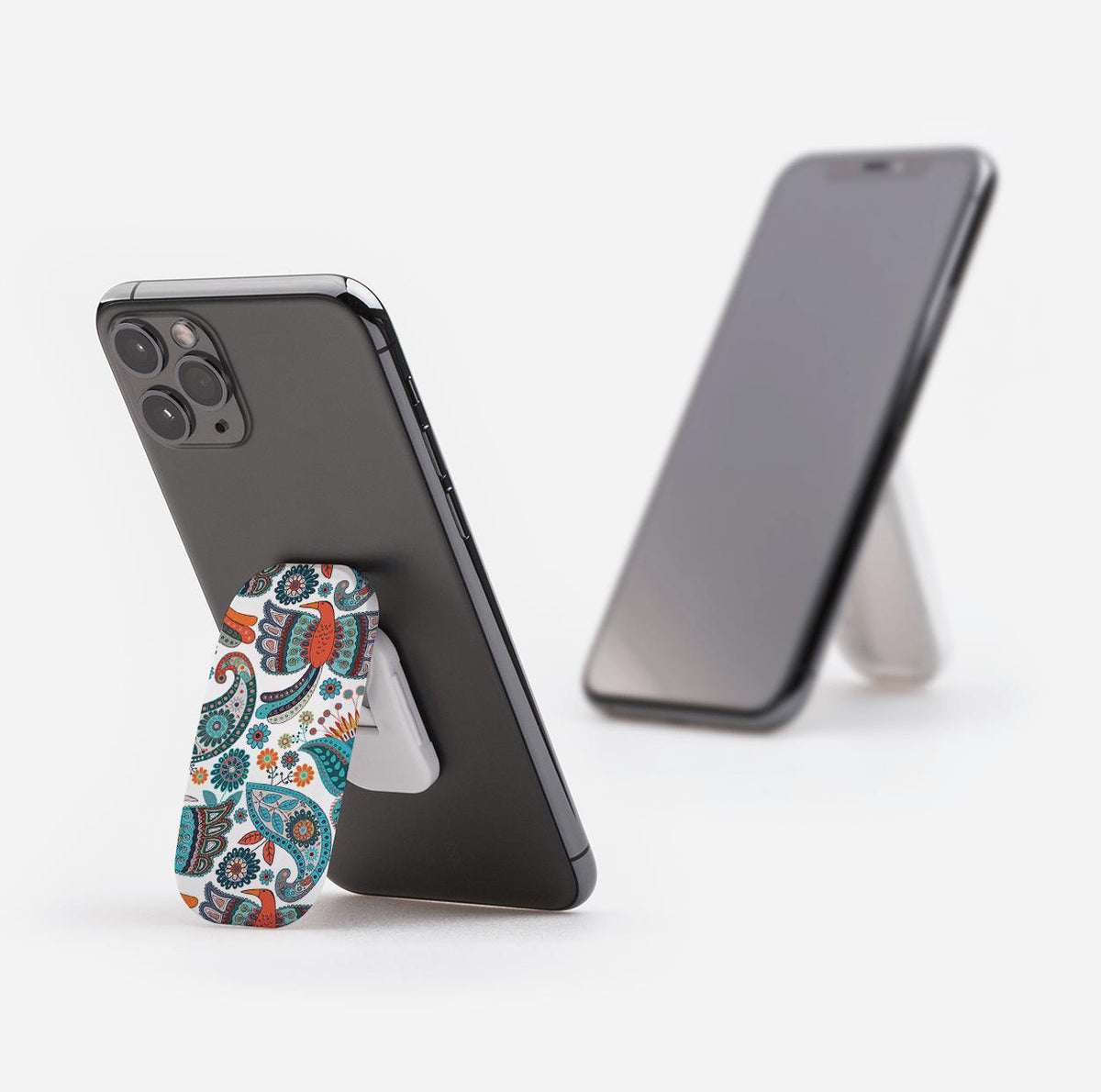 Avoch phone stand with a colorful paisley pattern attached to the back of a smartphone, acting as a kickstand.