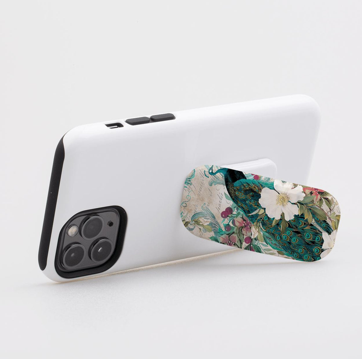 Oval phone stand attached to a white smartphone, featuring a vintage peacock and floral design in teal, green, and white.