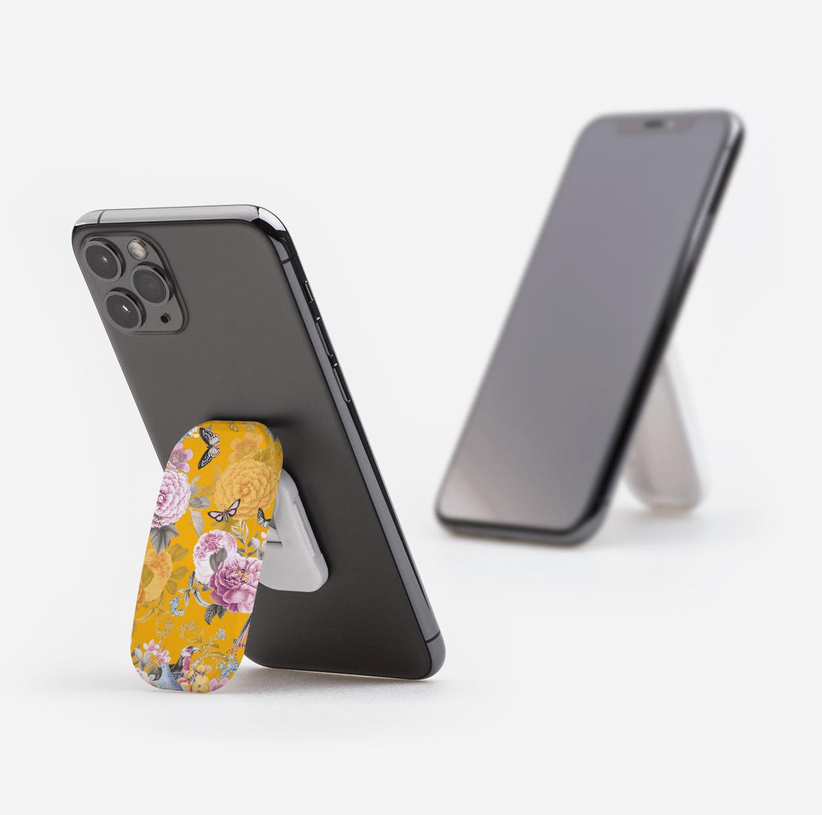 Barnes phone stand in a yellow floral print attached to a smartphone, functioning as a kickstand on a white background.