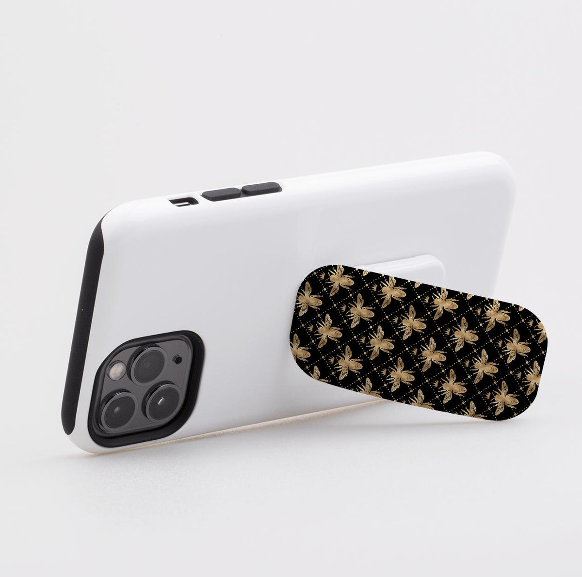 Clickit phone stand with a black and gold bee pattern attached to the back of a white smartphone.