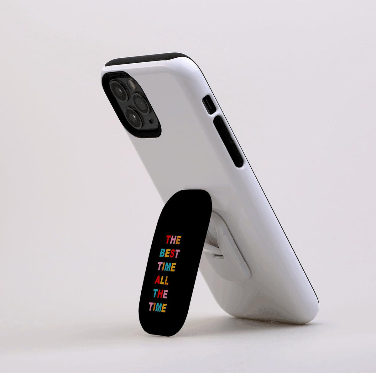 Black Flickit phone stand with colorful text reading The Best Time All The Time attached to a white smartphone.