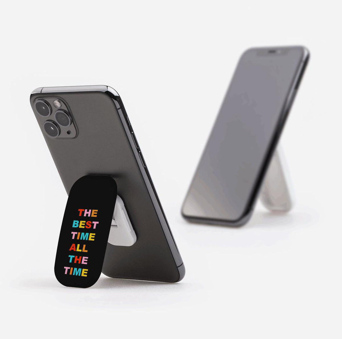 Black Flickit phone stand with colorful The Best Time All The Time text, attached to a smartphone in landscape mode.