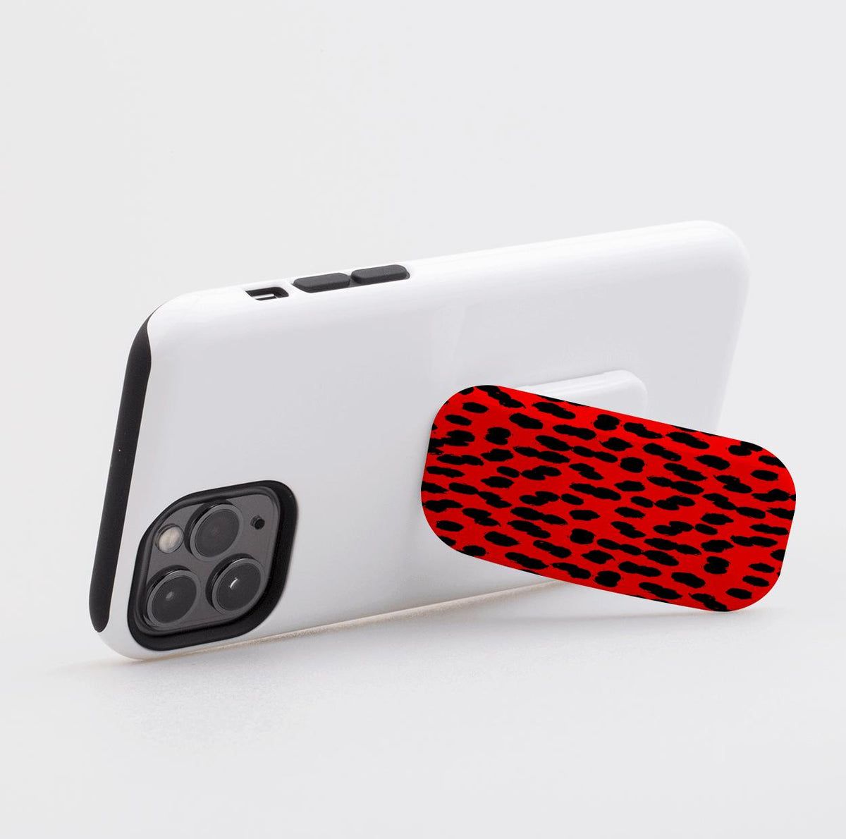 Black and red patterned Flickit phone stand attached to a white smartphone case, shown in landscape stand mode.