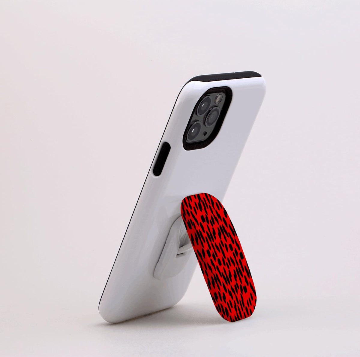 Black and red leopard print Flickit phone stand attached to the back of a white smartphone acting as a kickstand.