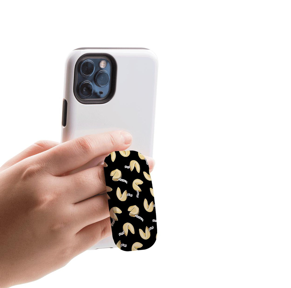 Schwarzer Flickit Handyhalter mit einem Glückskeks-Muster, an der Rückseite eines weißen Smartphones befestigt, das in einer Hand gehalten wird.