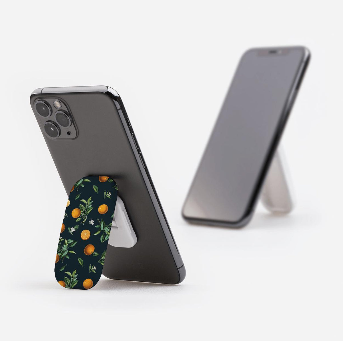 Black Orchard phone stand with an orange fruit pattern attached to the back of a smartphone acting as a kickstand.