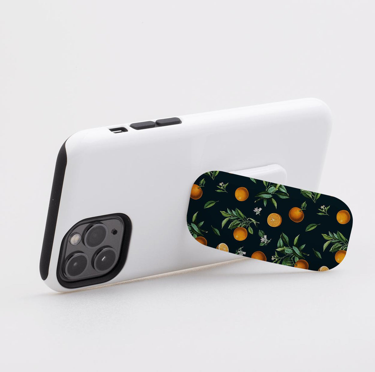 Black Orchard phone stand attached to a white smartphone case with an orange fruit and leaf pattern on a dark background.