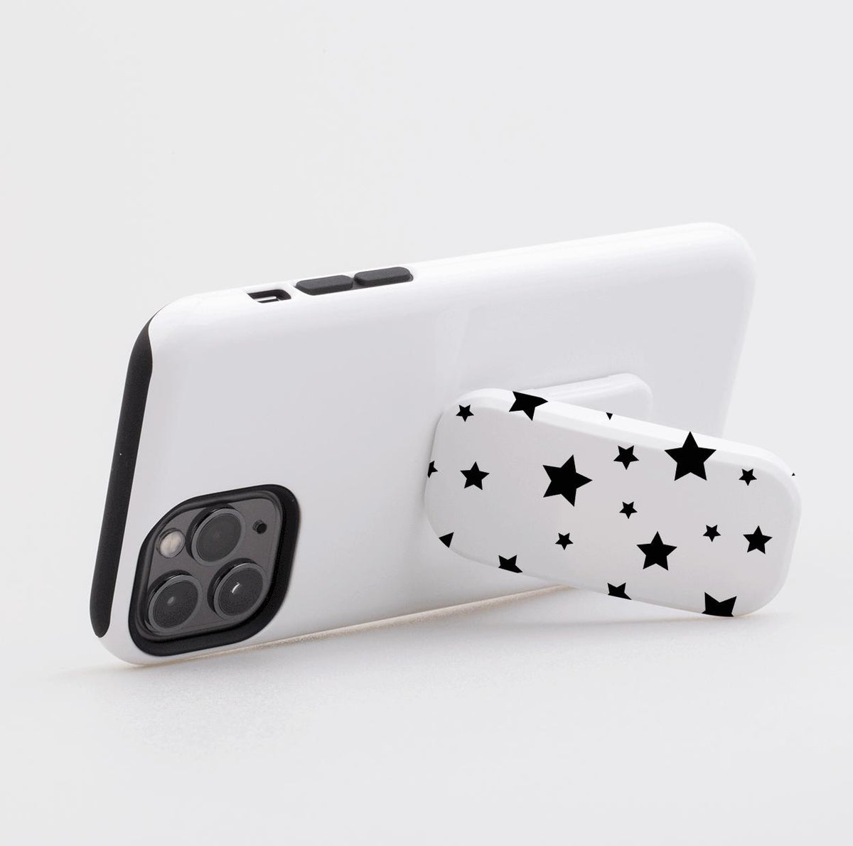 White phone case with a black star pattern Flickit stand propped in landscape mode on a white background.