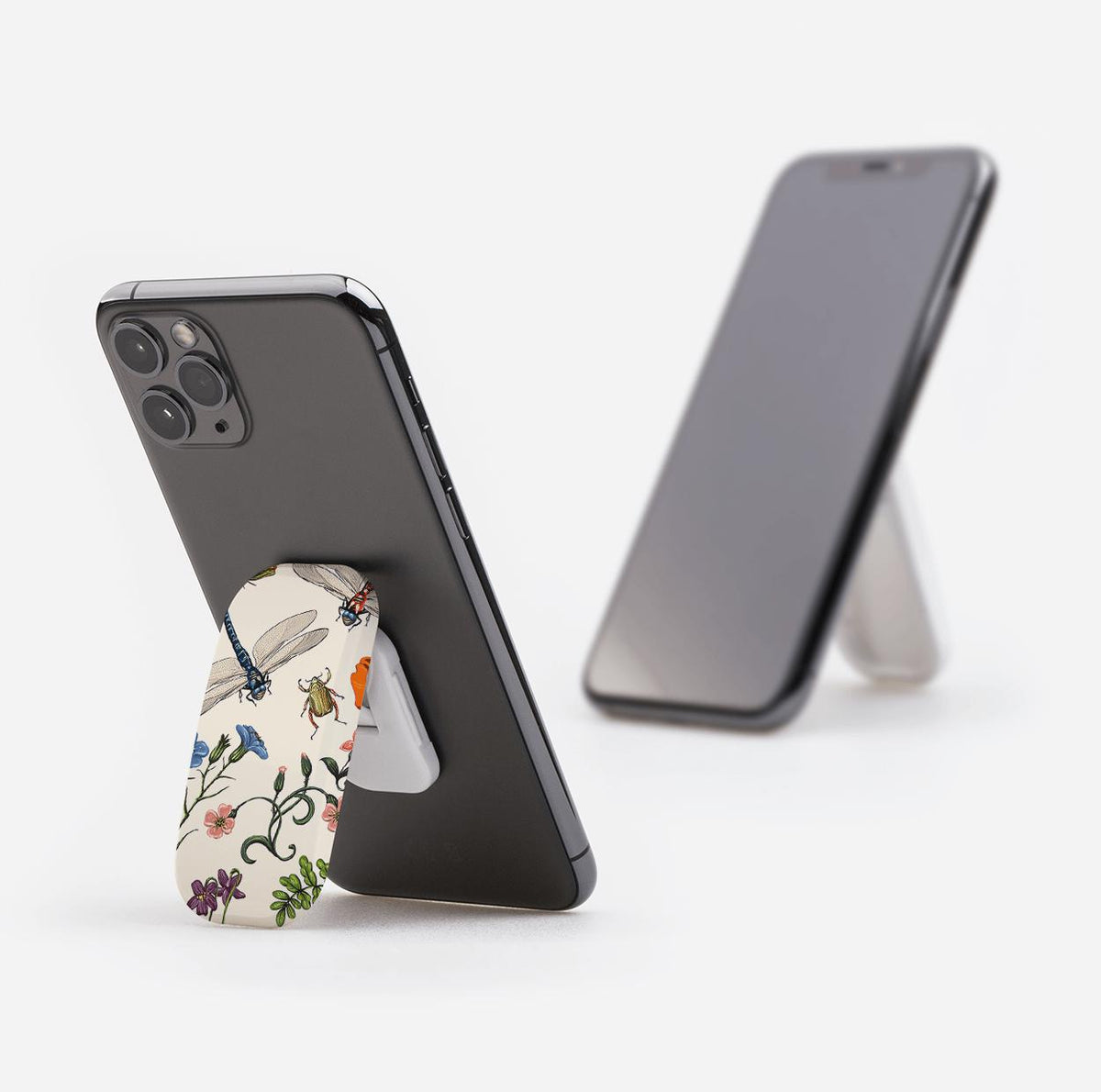 Bodnant Clickit phone stand with a cream floral and insect print, attached to the back of a black smartphone.