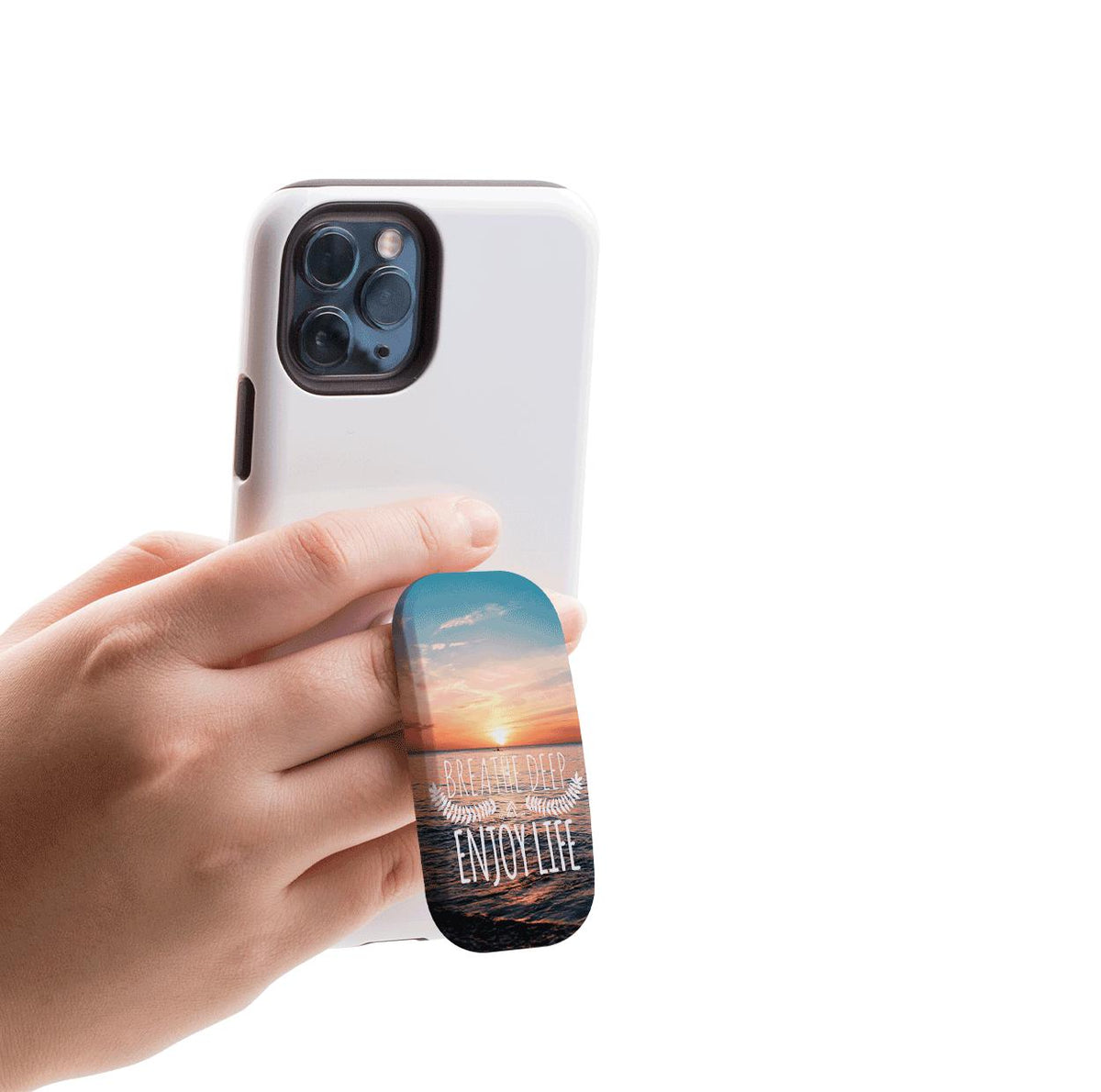Hand holding a white smartphone with an oval Flickit stand featuring a sunset ocean print and Breathe Deep text.