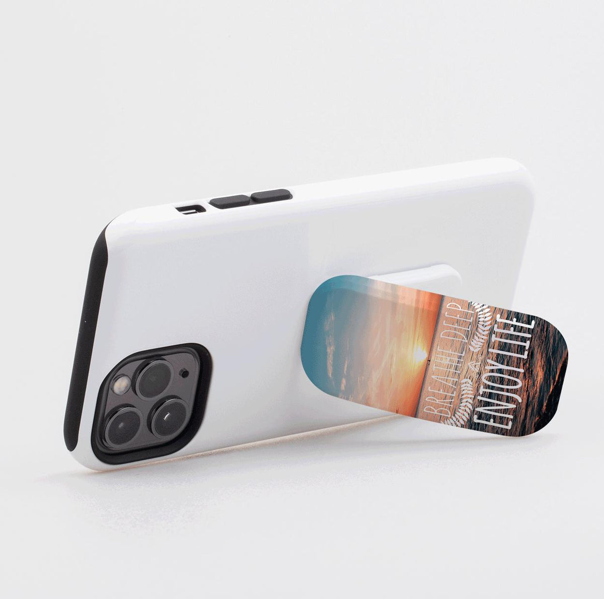 Breathe Deep Flickit phone stand on a white smartphone, featuring a sunset beach design with white text.