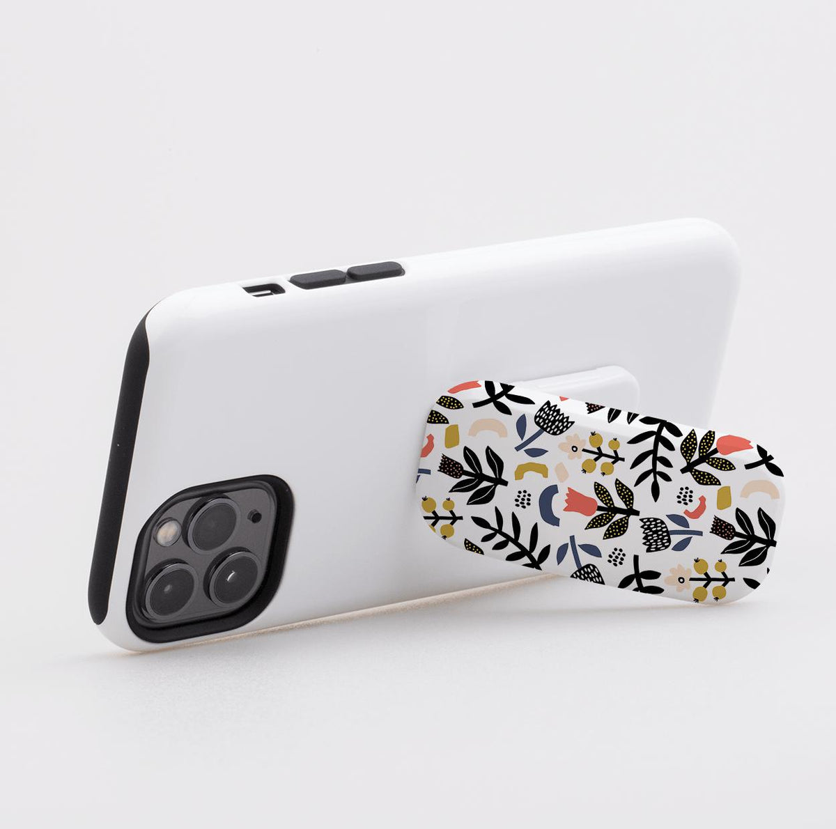 Broad Oak phone stand with a colorful floral and leaf pattern attached to the back of a white smartphone case.