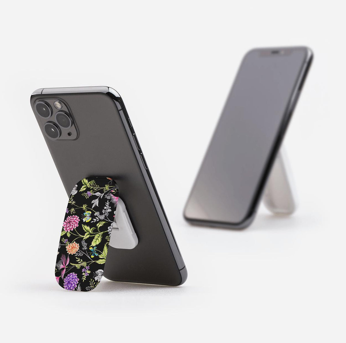 Broadview phone stand with a black floral pattern attached to the back of a smartphone, propping it up on a white surface.