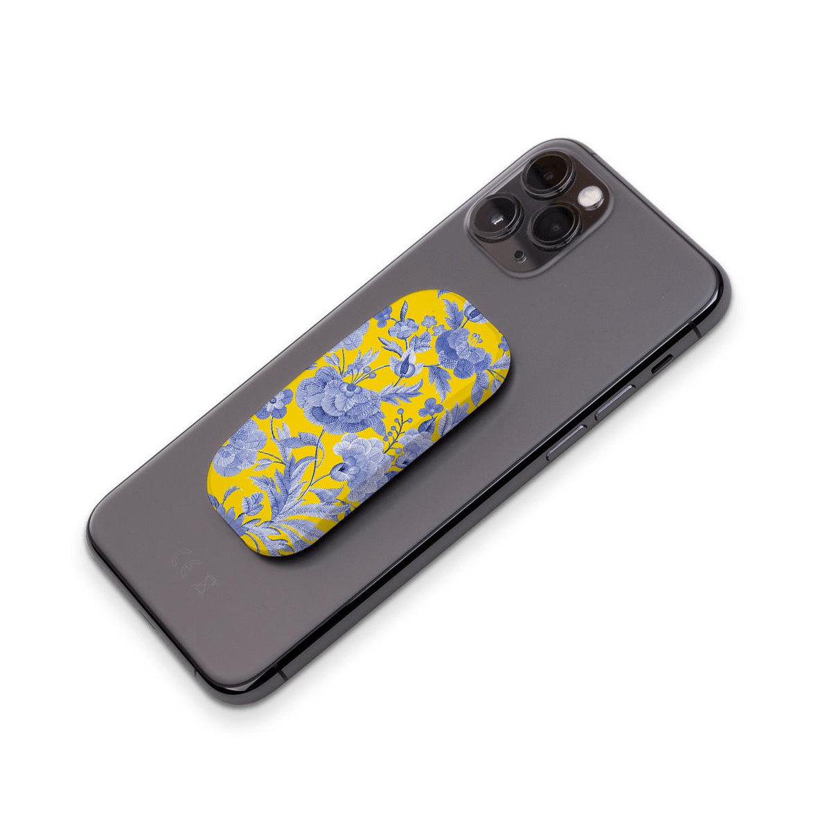 Chartwell Flickit phone stand with a vibrant yellow and blue floral pattern attached to the back of a black smartphone.