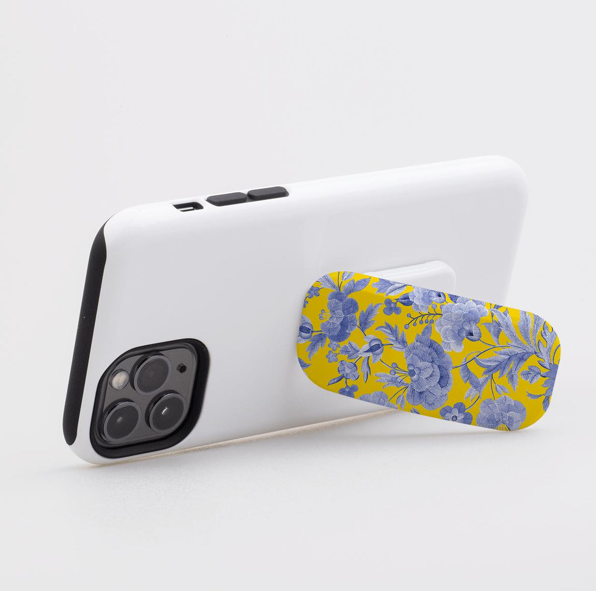 Chartwell Flickit phone stand with a yellow and blue floral pattern attached to the back of a white smartphone.
