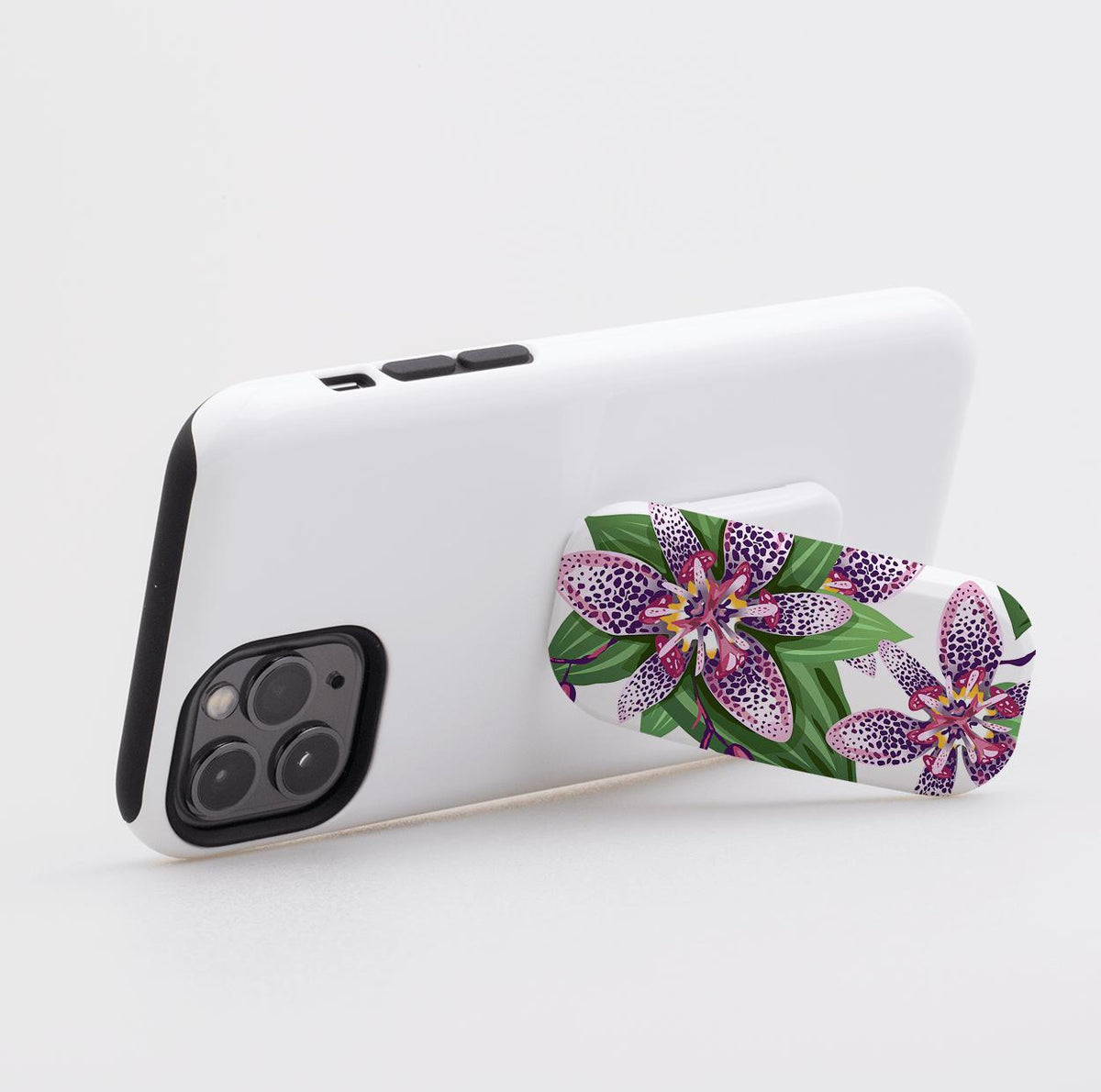 Support de téléphone Clickit floral Chelsea fixé à un étui de smartphone blanc, maintenu en mode paysage.