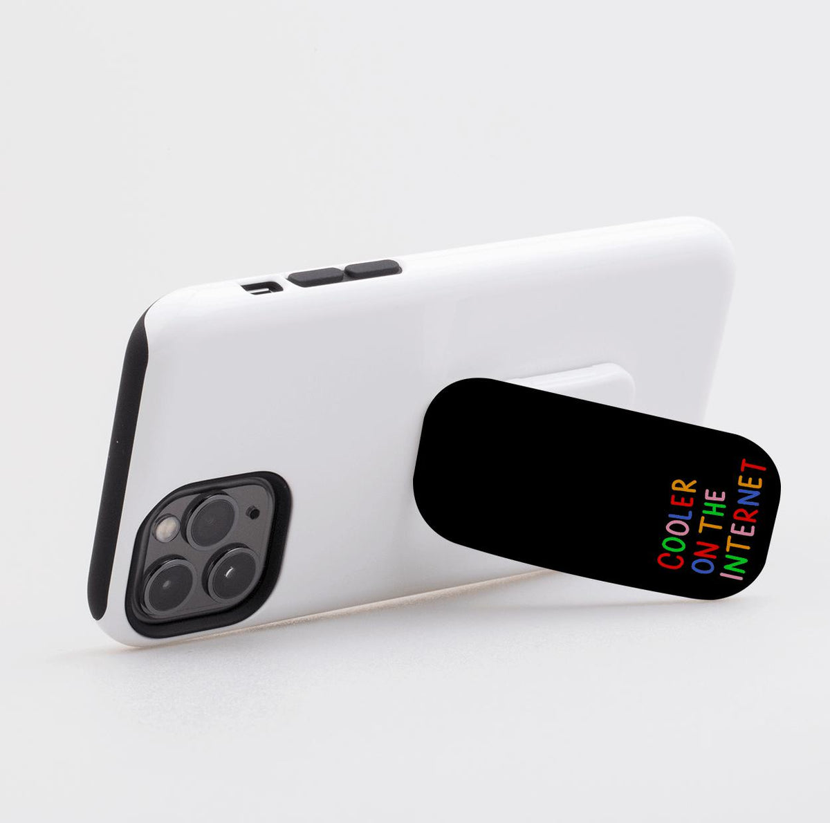 Black Flickit phone stand attached to a white smartphone, featuring the colorful text Cooler On The Internet.