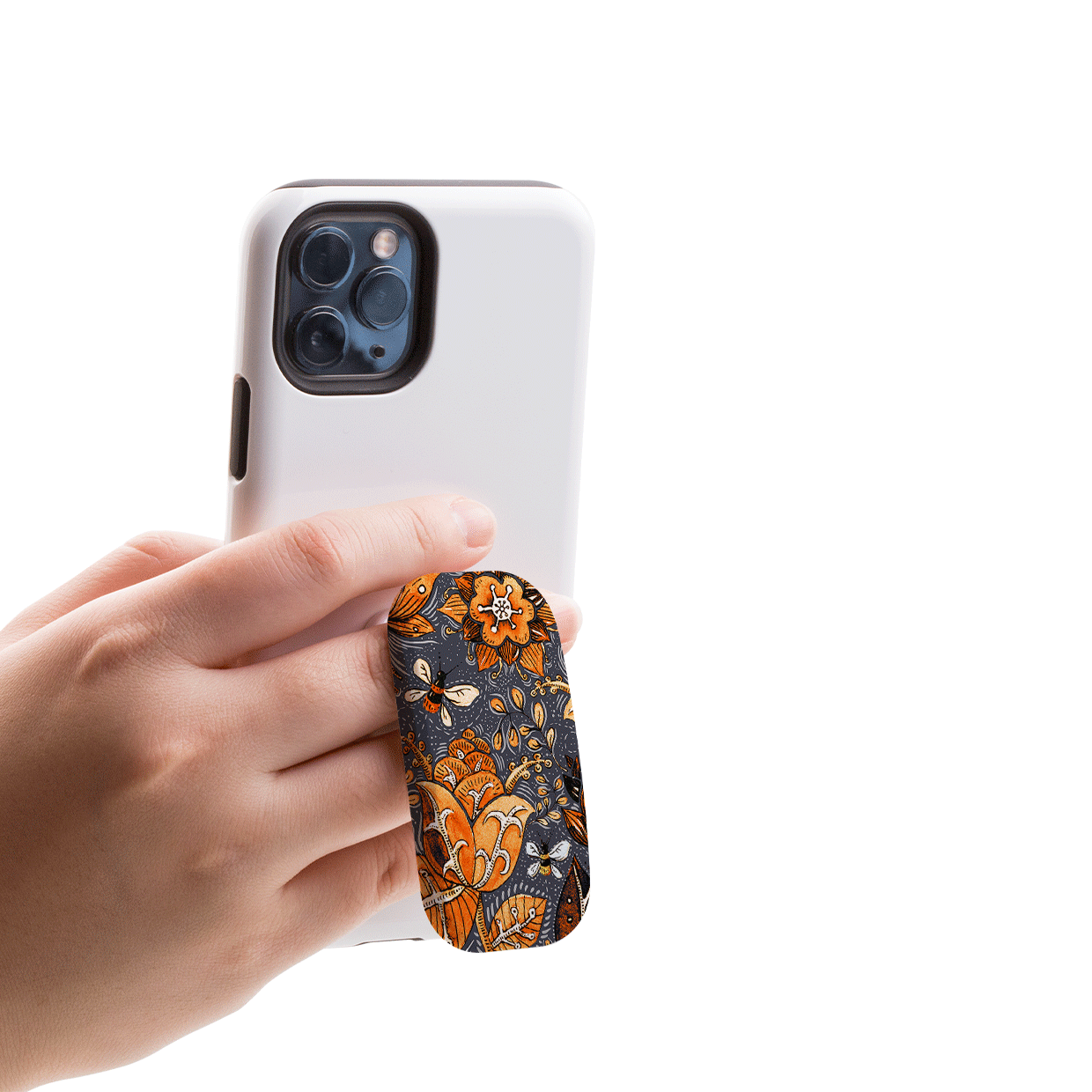 Hand holding a white smartphone with an orange and grey floral patterned Flickit phone stand attached to the back.