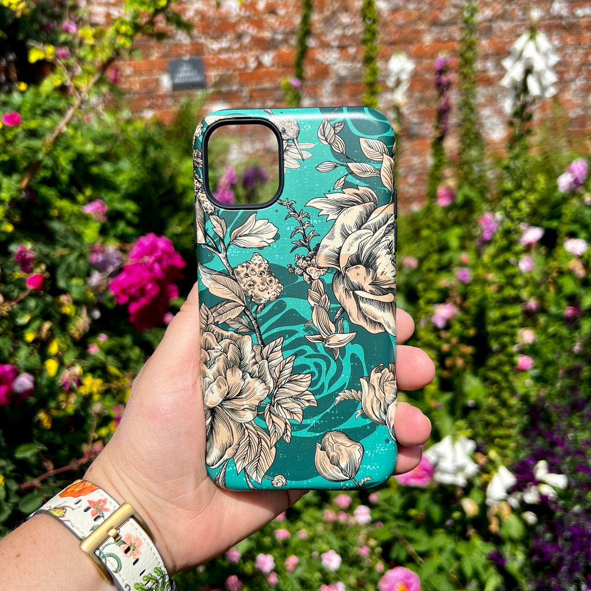 iPhone Tough Case in Highgrove Gardens floral print with a teal background and beige line-art flowers held in a garden.