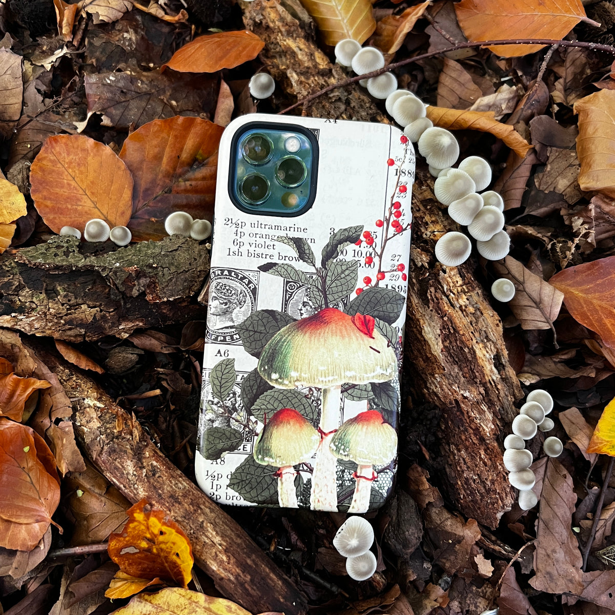 iPhone tough case featuring vintage mushroom illustrations and botanical text on a forest floor with autumn leaves.