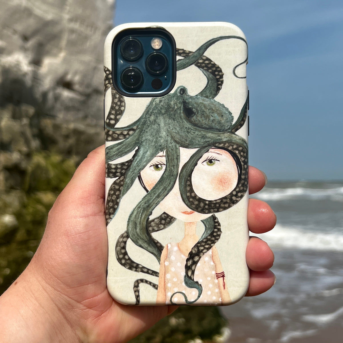 Dual-layer iPhone tough case featuring Katherine Quinn’s Octopus Girl art with a girl and green octopus on a beach background.