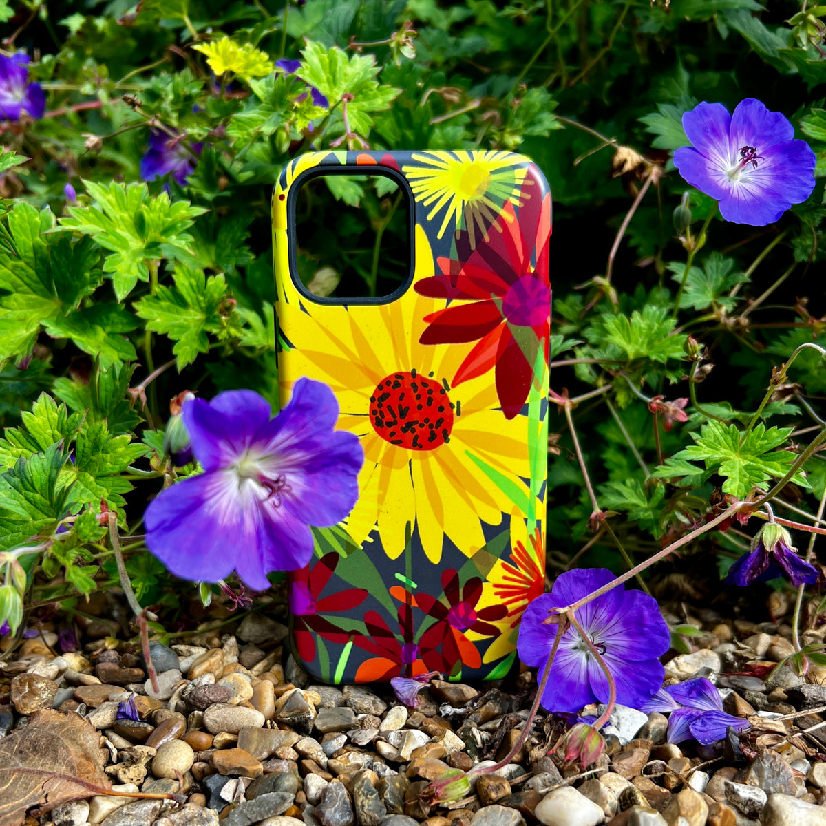 iPhone Tough Case featuring vibrant yellow sunflower artwork by Sarah Campbell, set against a backdrop of purple flowers.