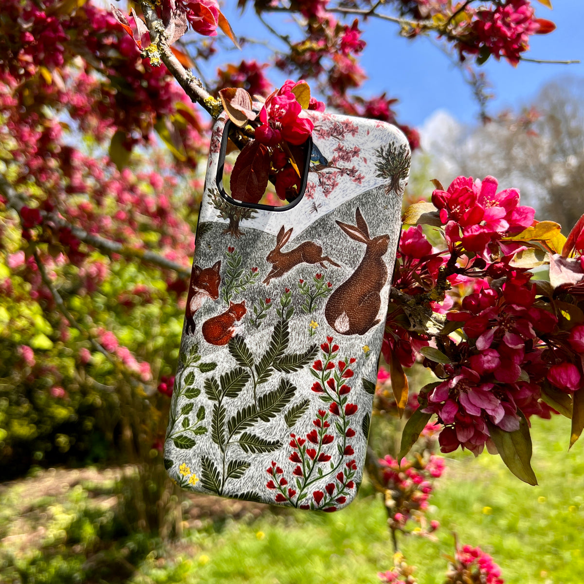 iPhone Tough Case featuring Catherine Rowe’s Sussex Downs wildlife art with rabbits and foxes, hanging in a flowering tree.