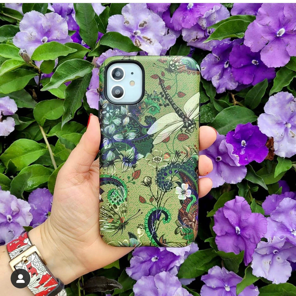 Vyne iPhone tough case with dragonfly and floral art held against a background of purple flowers.