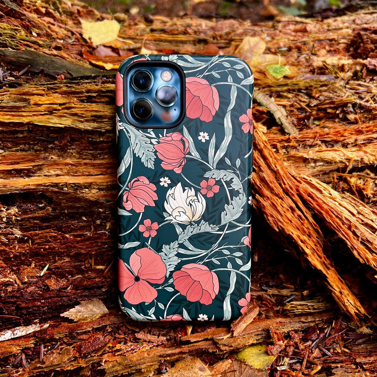 iPhone Tough Case in Woodcroft floral print with pink flowers and green foliage on a dark teal background.