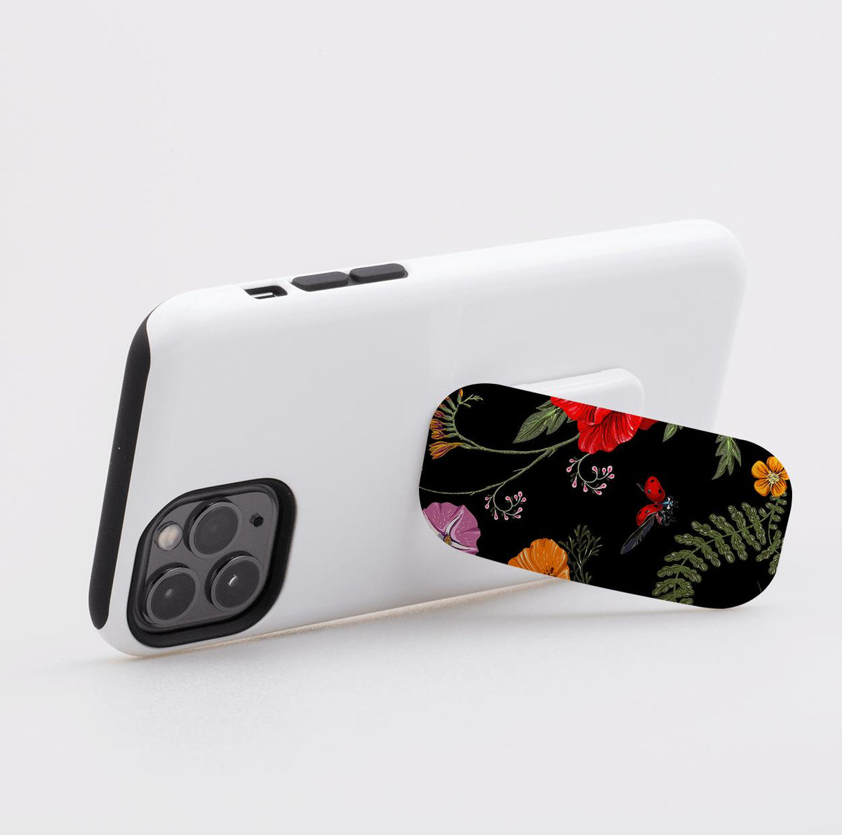 Moonlight Garden phone stand with floral and ladybug print attached to the back of a white smartphone.