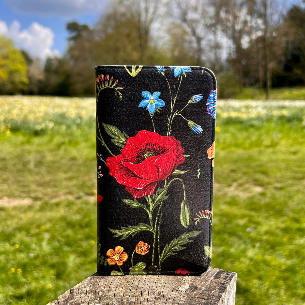 Moonlight Garden vegan leather folio phone case with vibrant red poppy and floral print on a black satin finish.