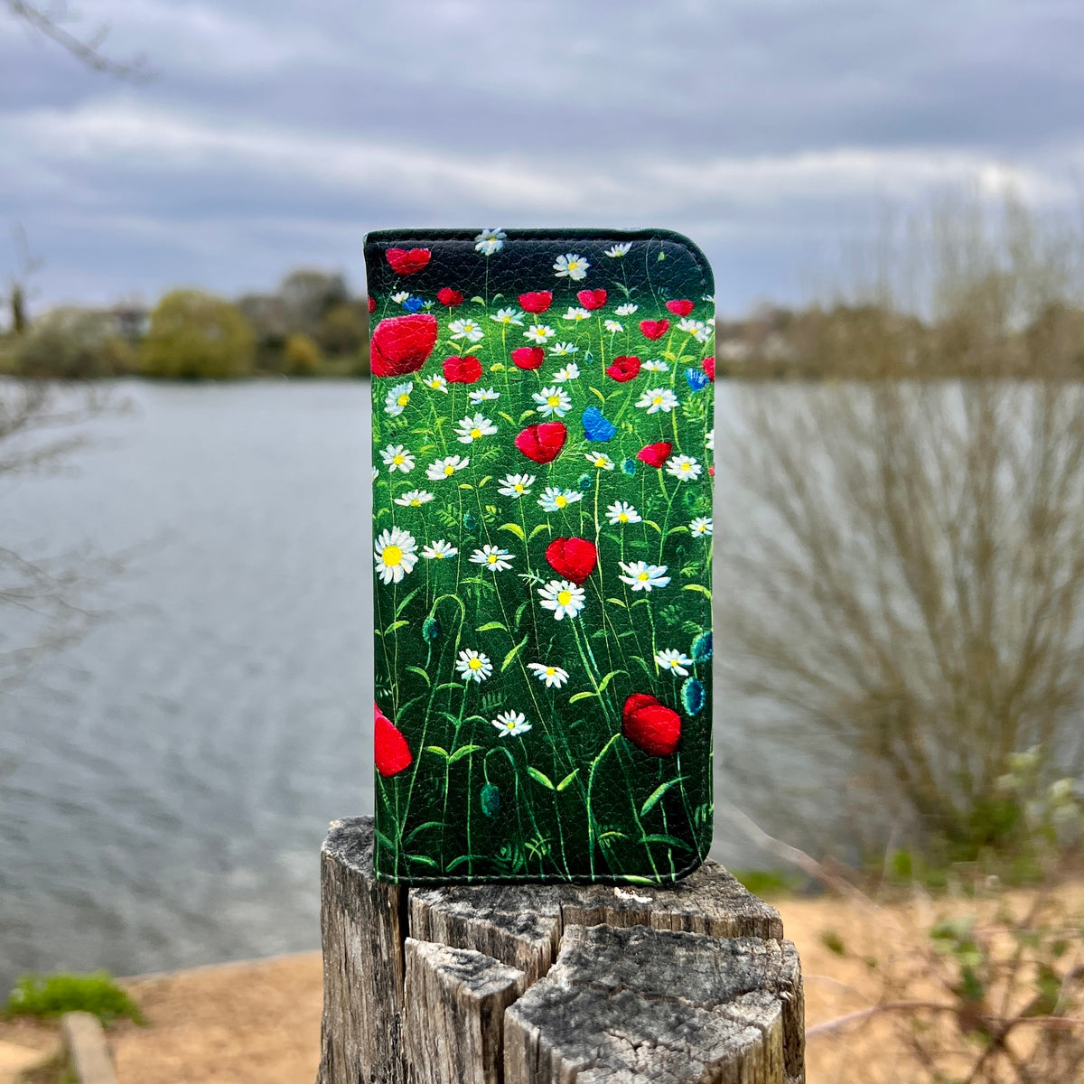 Vegan leather folio phone case featuring a vibrant poppy and daisy meadow print with a smooth satin finish.