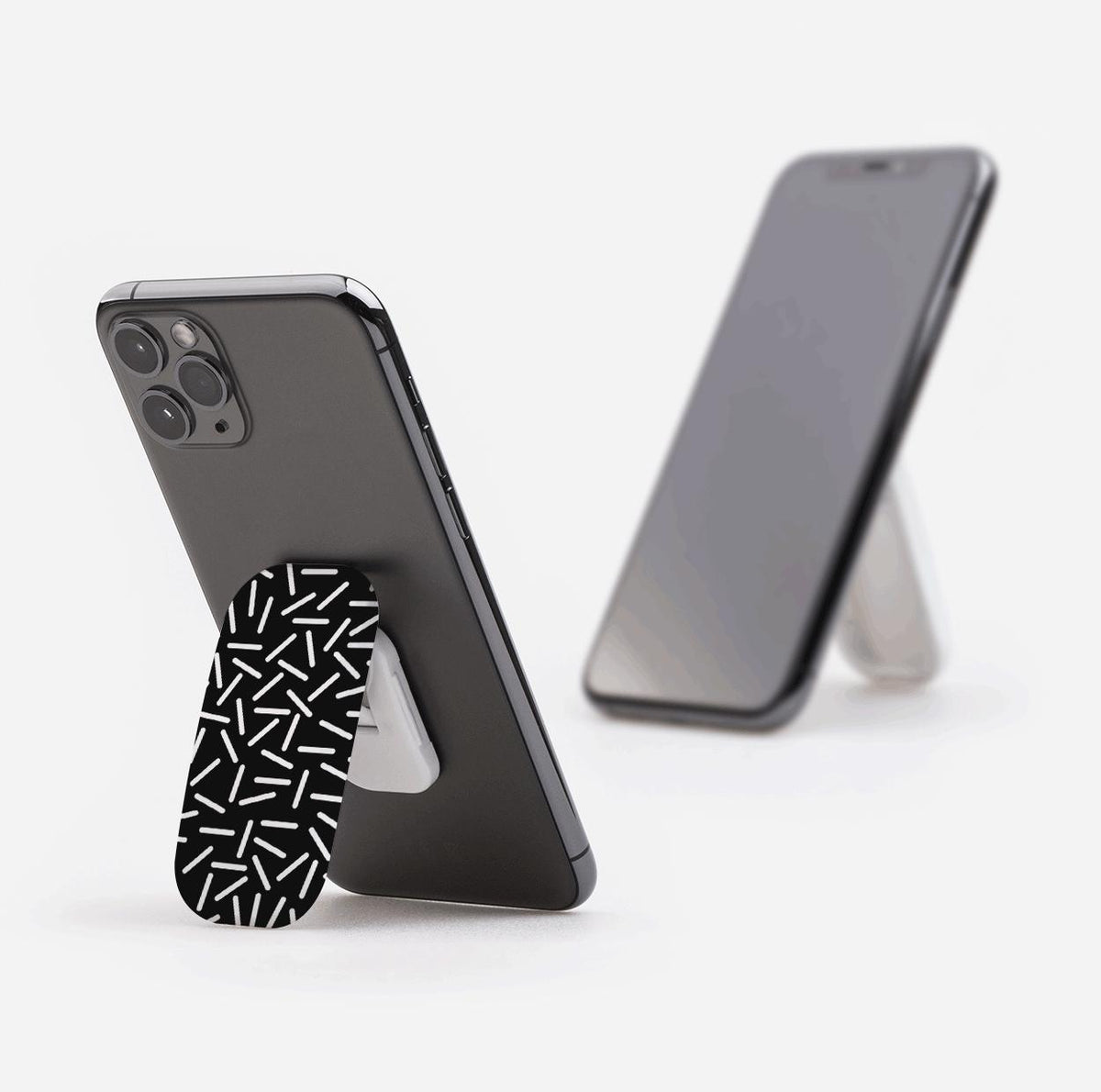 Black Flickit phone stand with white confetti pattern attached to the back of a smartphone, acting as a kickstand.