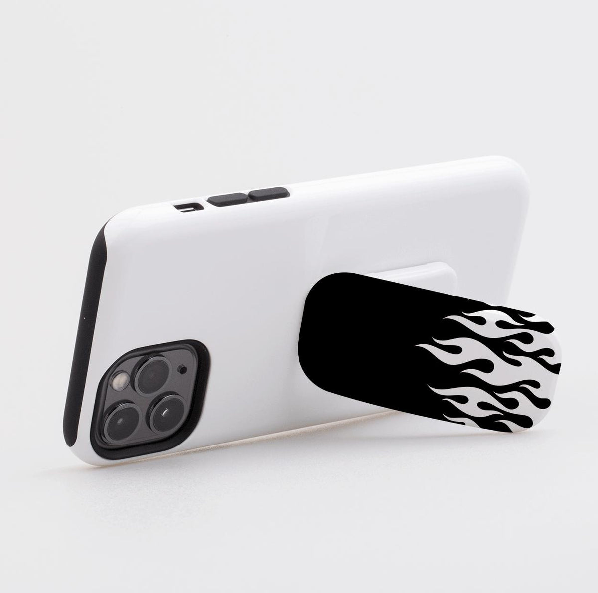 Black phone stand with a white flame pattern attached to the back of a white smartphone case on a light background.